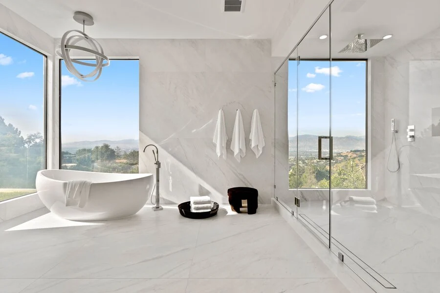 Freestanding Tub &mdash; A glass-walled shower and valley view beyond.