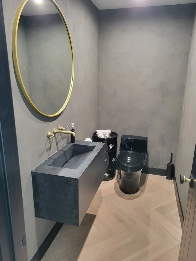 Powder Room &mdash; A round brass mirror against deep charcoal walls.