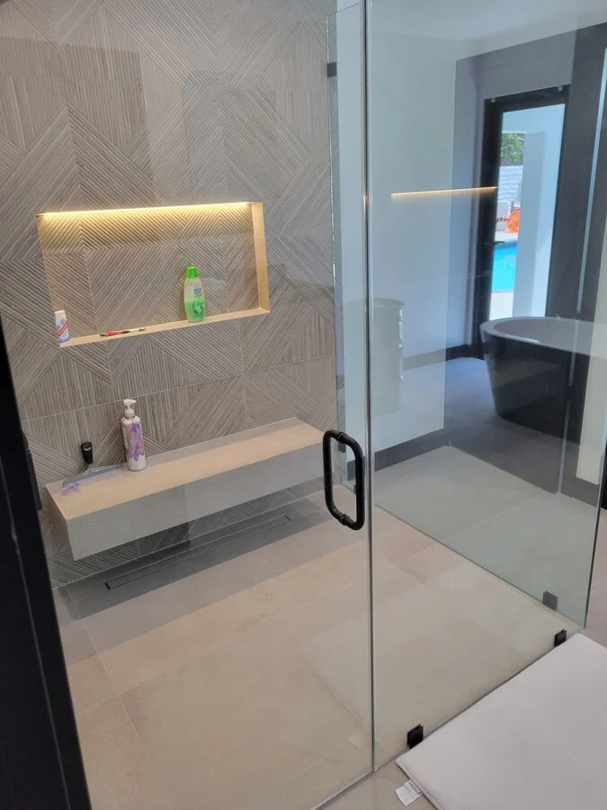 Powder Detail &mdash; A glass shower door and brushed brass hardware.