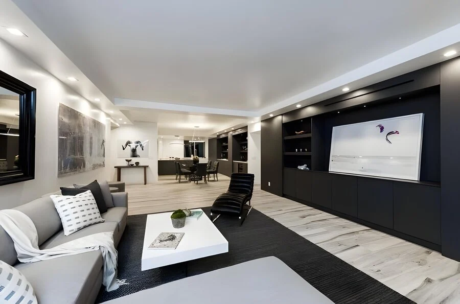 Living Room &mdash; A sectional and wall-mounted screen over warm flooring.