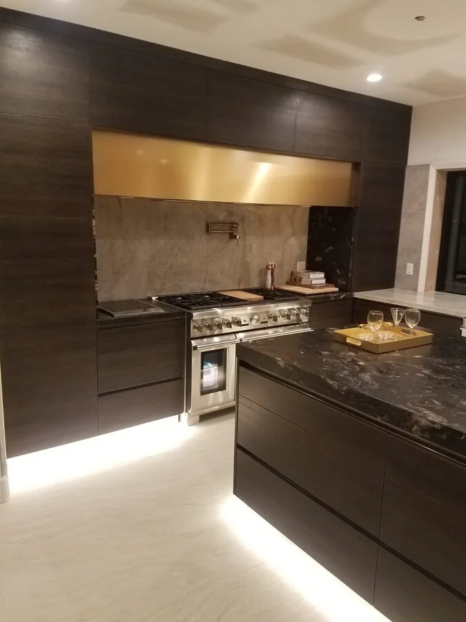 Ebonized Cabinetry &mdash; Blackened cabinetry with a brass hood and under-lighting.