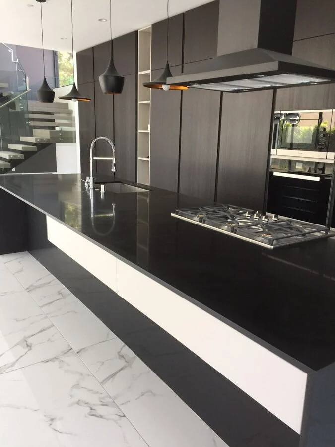 Island & Staircase &mdash; A dark marble island beside an open stair.