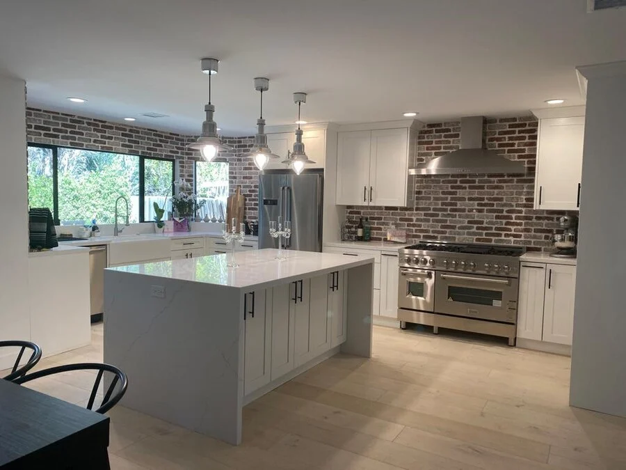 Brick Backsplash &mdash; Exposed brick against white shaker cabinetry.