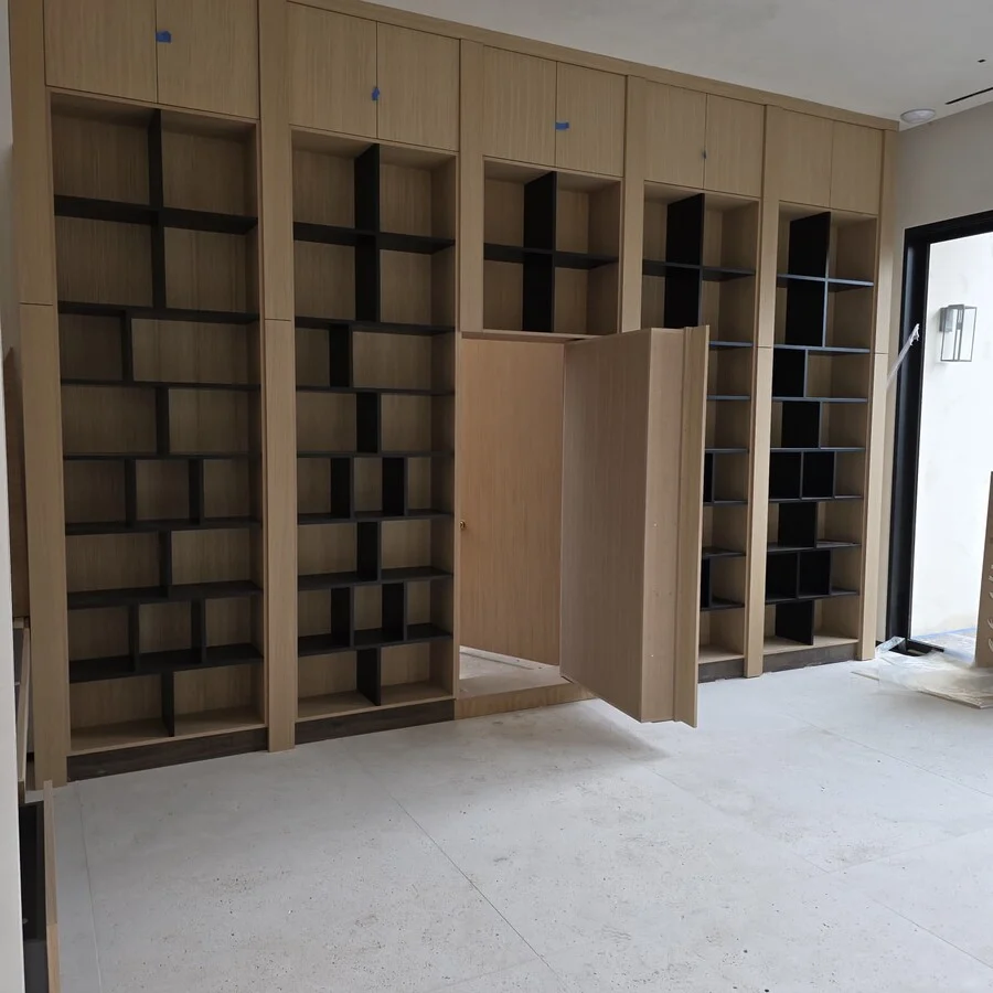 Custom Millwork &mdash; A walnut-tone library wall with a hidden door.