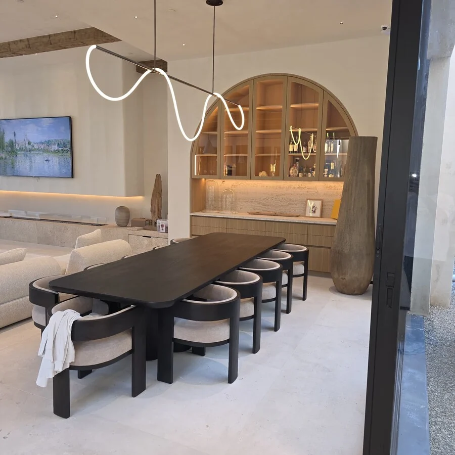 The Dining Room &mdash; A live-edge table beneath a curved pendant light.