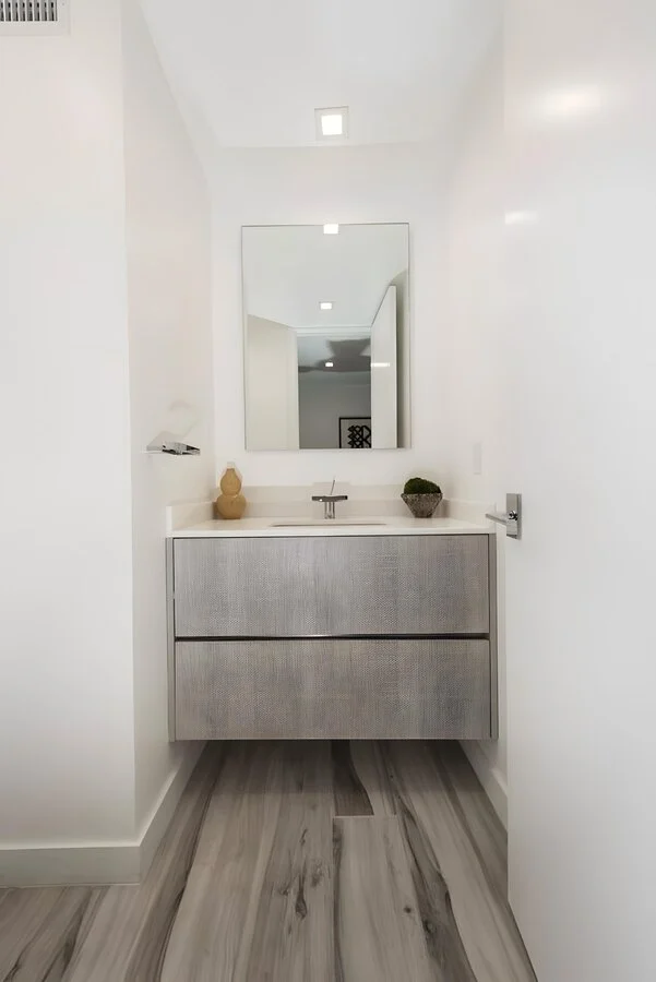 Powder Room &mdash; A floating vanity beneath a round mirror.